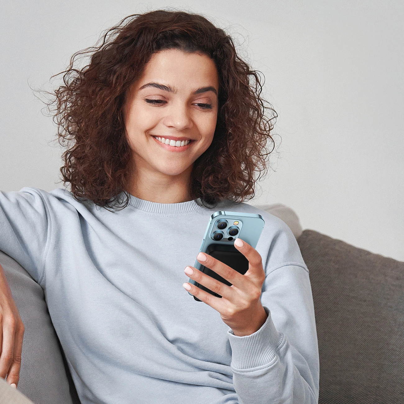 A smiling woman holds a phone with a Baseus Magnetic Mini induction Powerbank 10000mAh 30W attached